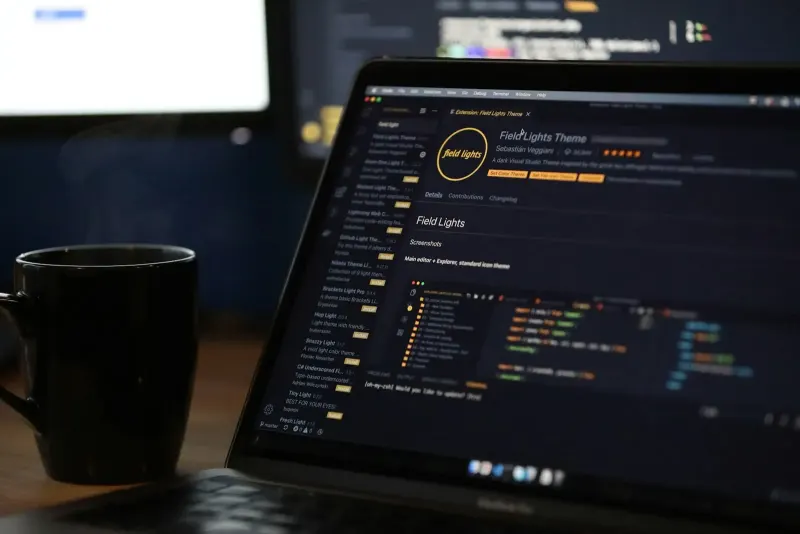 Laptop screen showing code next to a mug of coffee