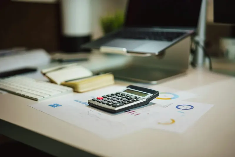 Calculator on a table next to a laptop